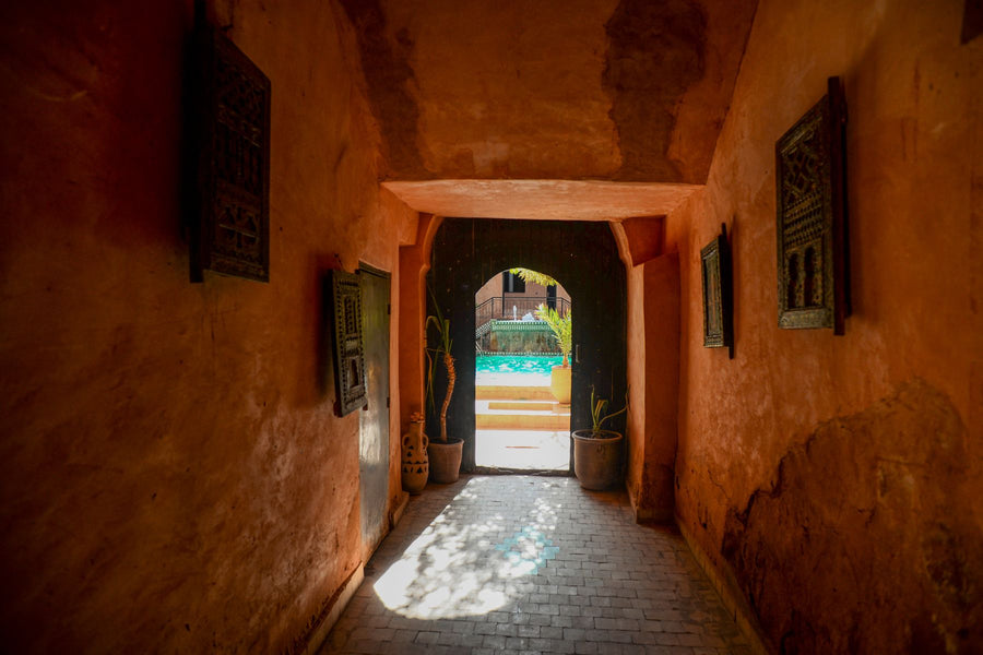 Sunlit Moroccan hallway opening onto a courtyard