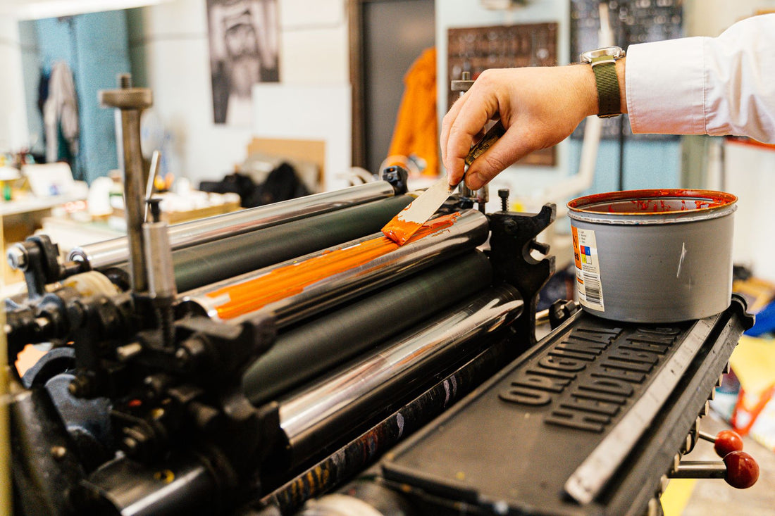 Ink being applied to the roller of a vintage printing press