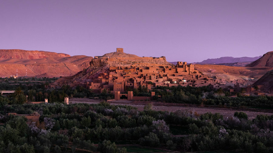 The kasbah of Aït Benhaddou among palm trees and mountains, a landscape like those painted by Abderrahim Saba